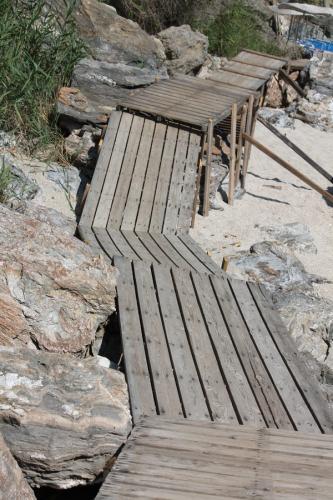 Hinter dem kleinen Hafen von Agios Ioannis führt dieser Brettersteg zum benachbarten Sandstrand.
